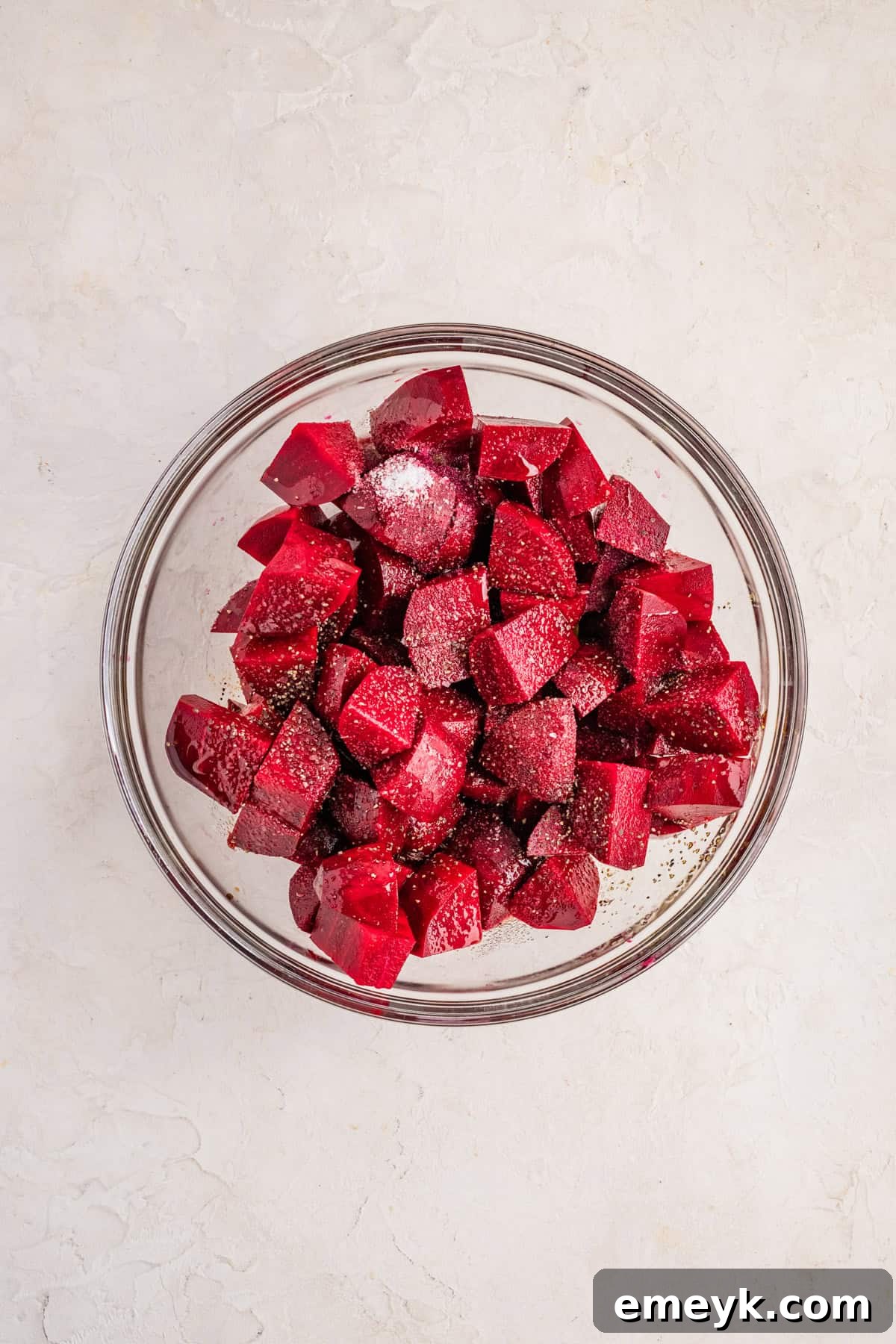 Quick and Easy Foil Free Roasted Beets 6 Raw, cubed beets being tossed with olive oil and balsamic vinegar in a large glass mixing bowl.