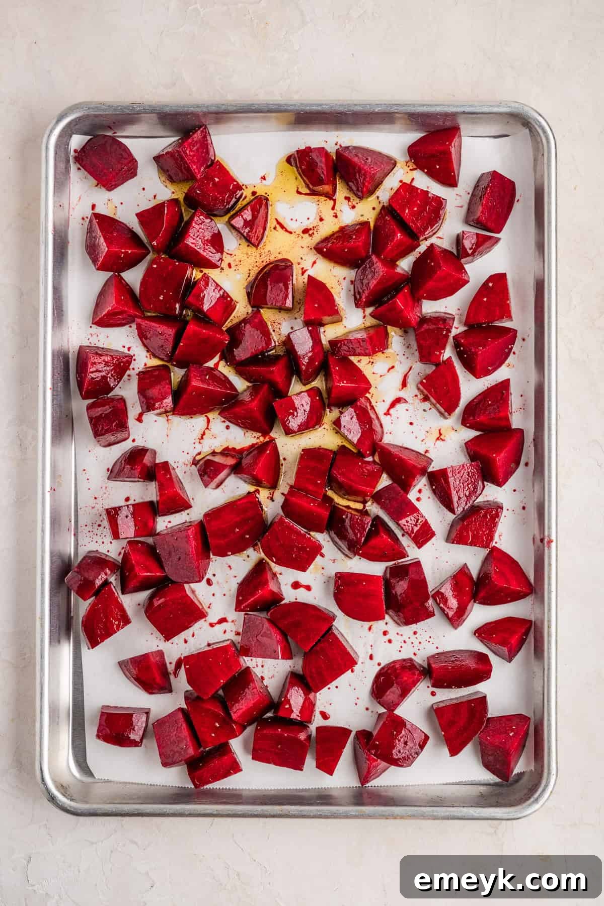 Quick and Easy Foil Free Roasted Beets 7 Seasoned raw beet cubes spread in a single layer on a parchment-lined baking sheet before roasting.