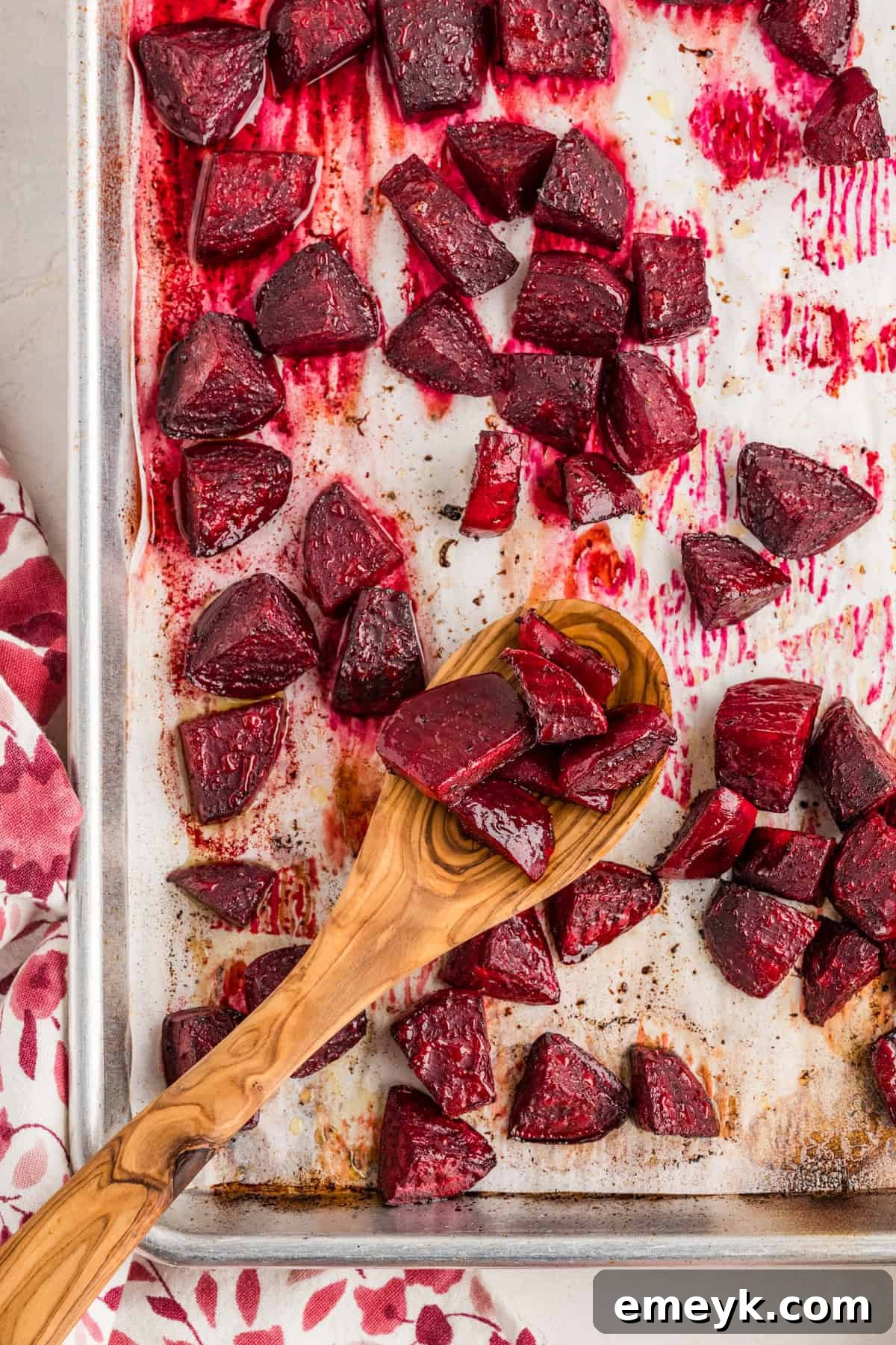 Quick and Easy Foil Free Roasted Beets 8 Perfectly roasted beets on a baking sheet, with a wooden spoon scooping some up.