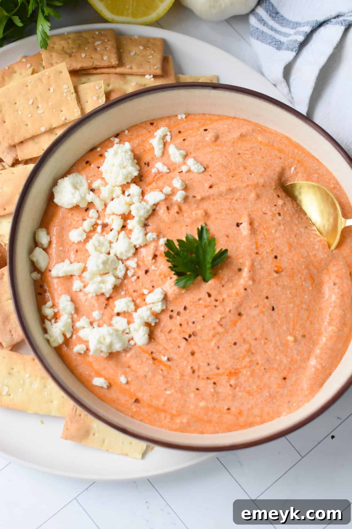 A close-up shot of the creamy and smooth texture of the roasted red pepper feta dip in a white bowl.