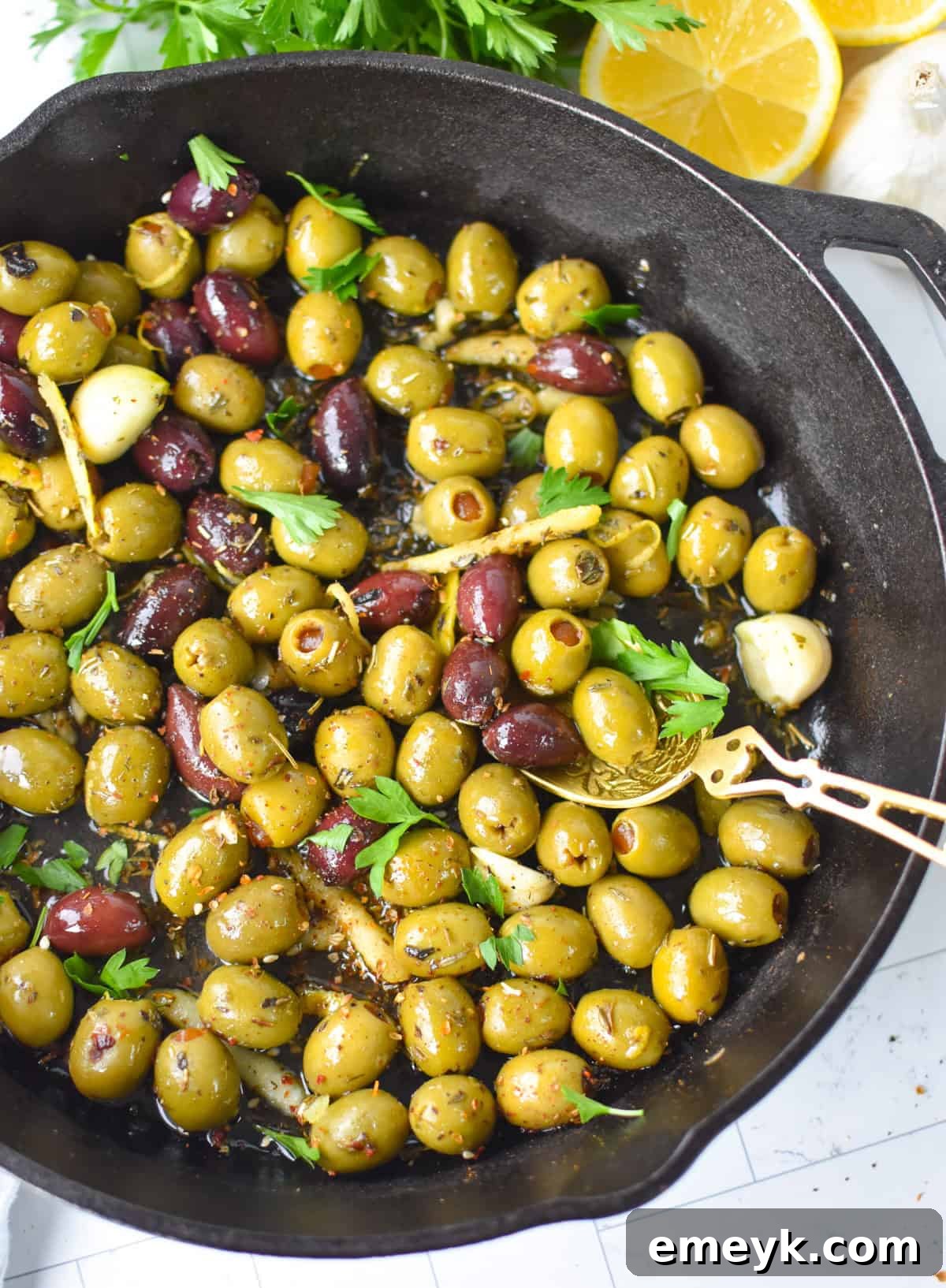 Warm olives with lemon and Mediterranean herbs in a skillet 