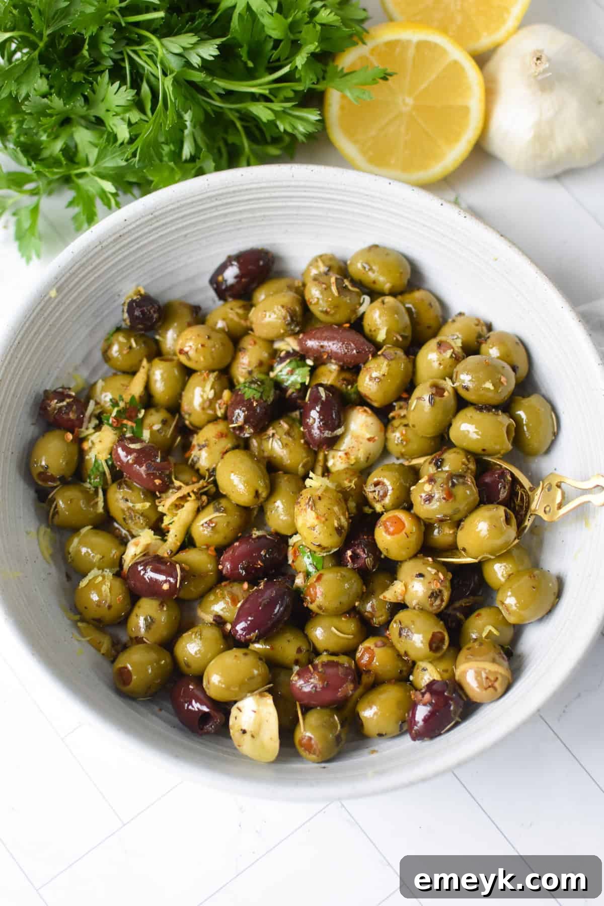 Warm olives with lemon and Mediterranean herbs in a white bowl