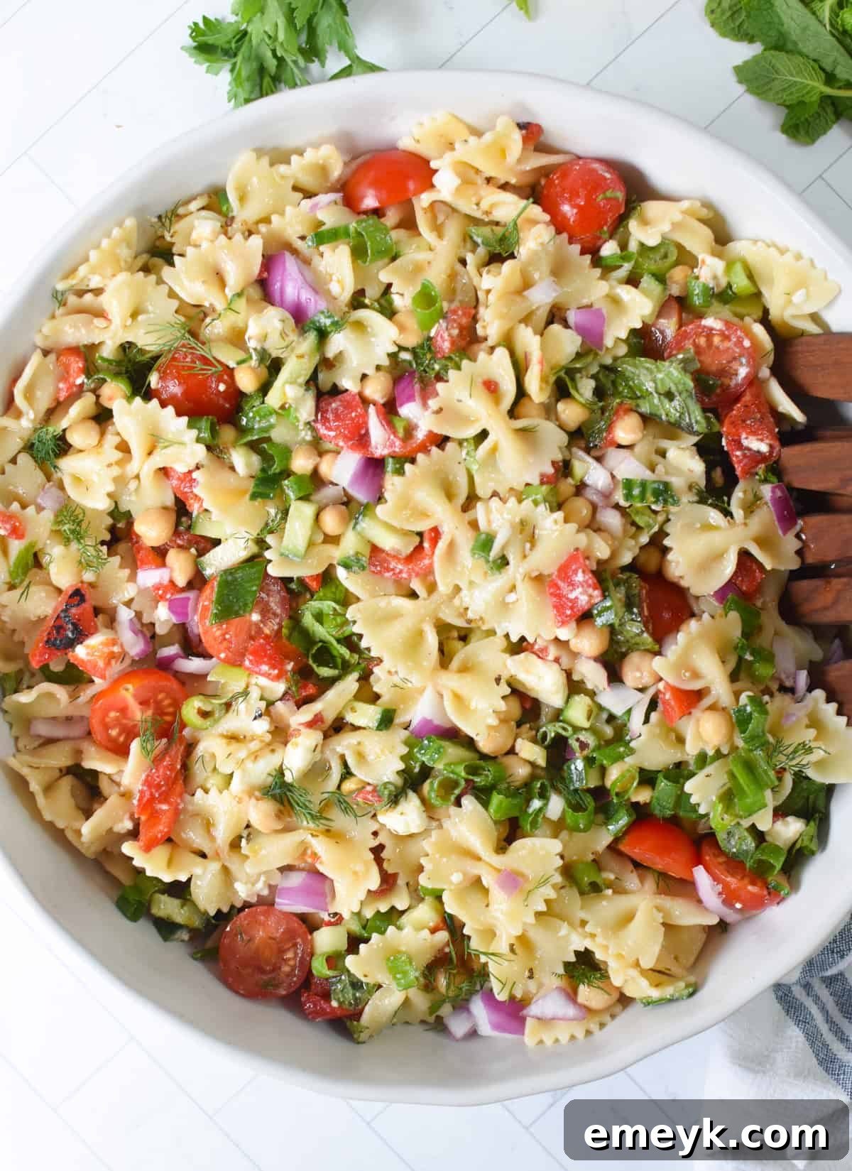 Mediterranean bow tie pasta salad in a large serving bowl with feta and fresh herbs