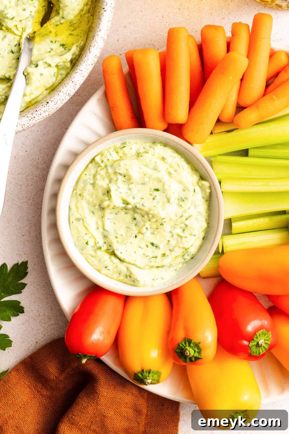 Green Goddess Dip with carrots, celery and bell peppers surrouding the dip 