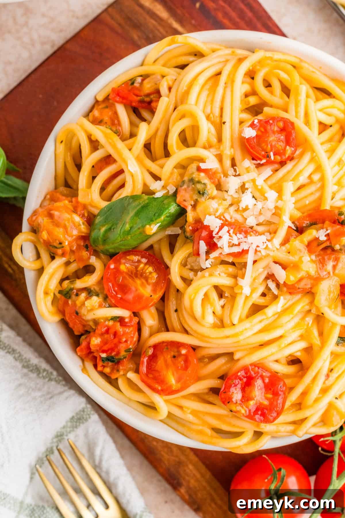 Bowl of cherry tomato basil pasta topped with fresh basil and shaved parmesan
