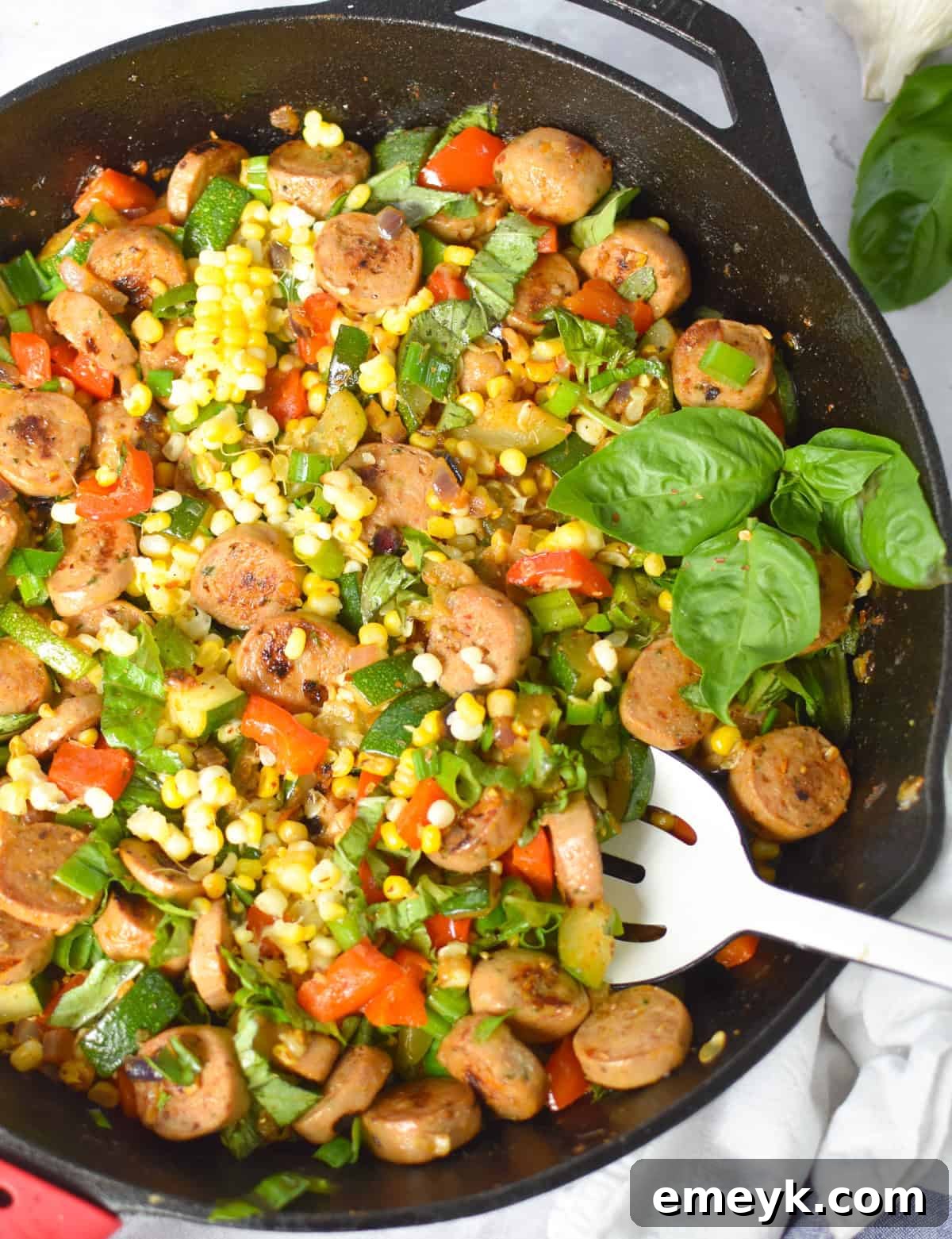 Cast iron skillet of sausage, zucchini, corn, and bell pepper ready to serve