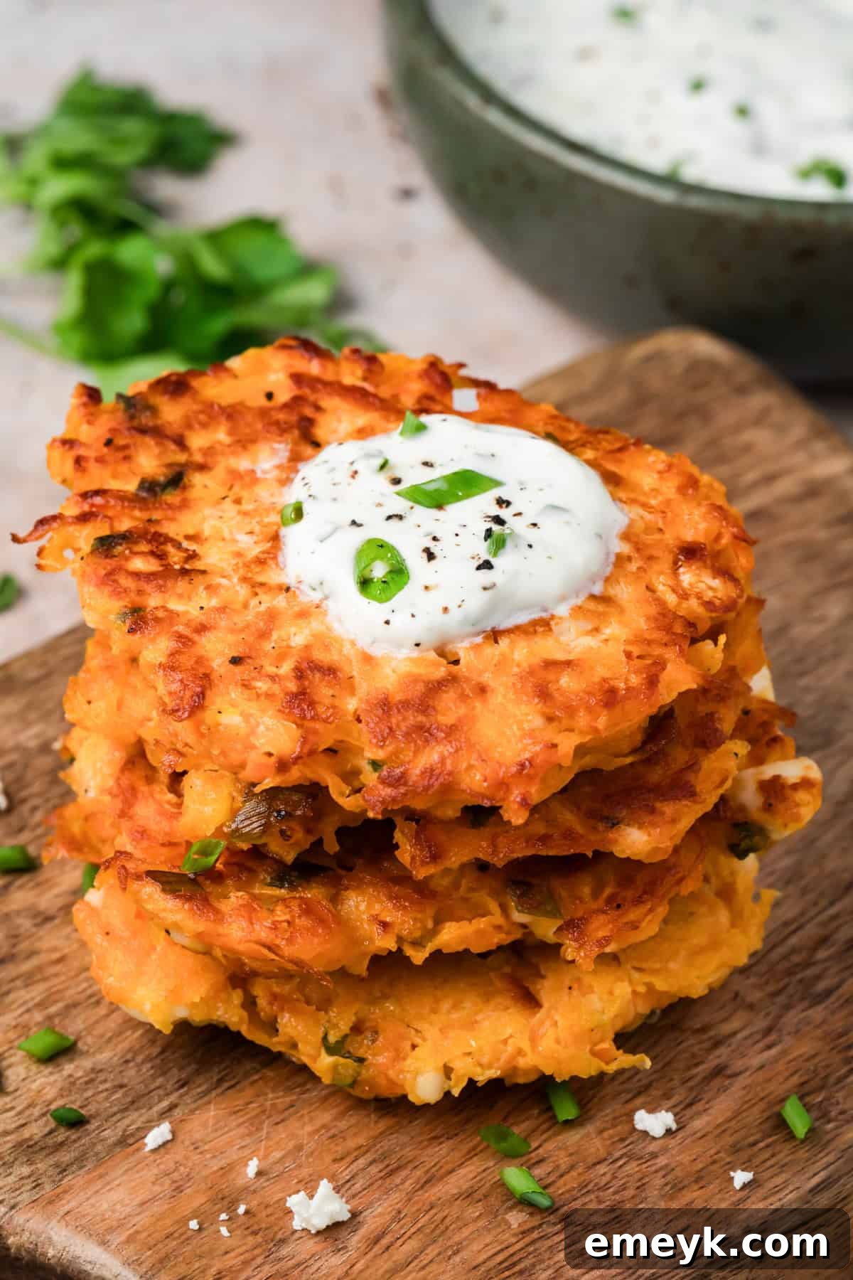 Crispy sweet potato fritters with feta stacked on a plate with lemon herb yogurt sauce