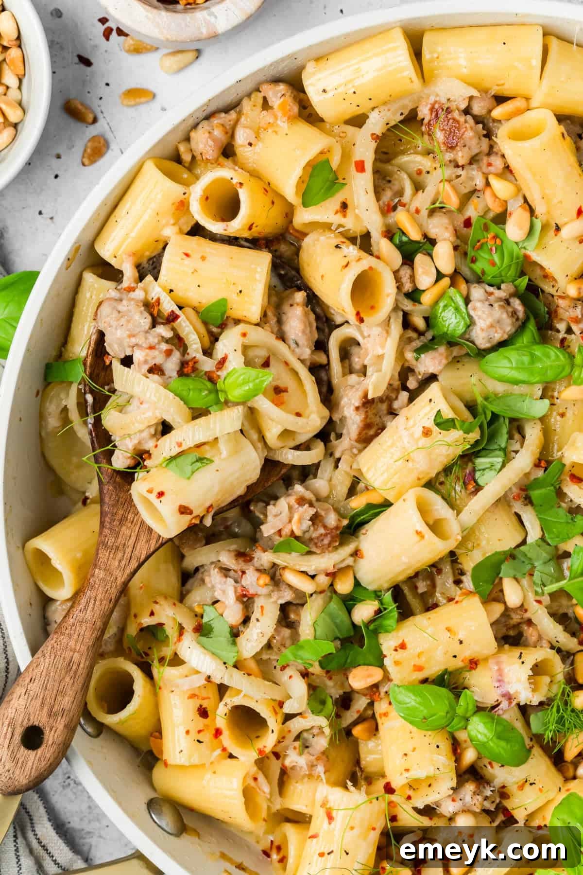 Close-up of creamy sausage and fennel pasta topped with toasted pine nuts and Parmesan